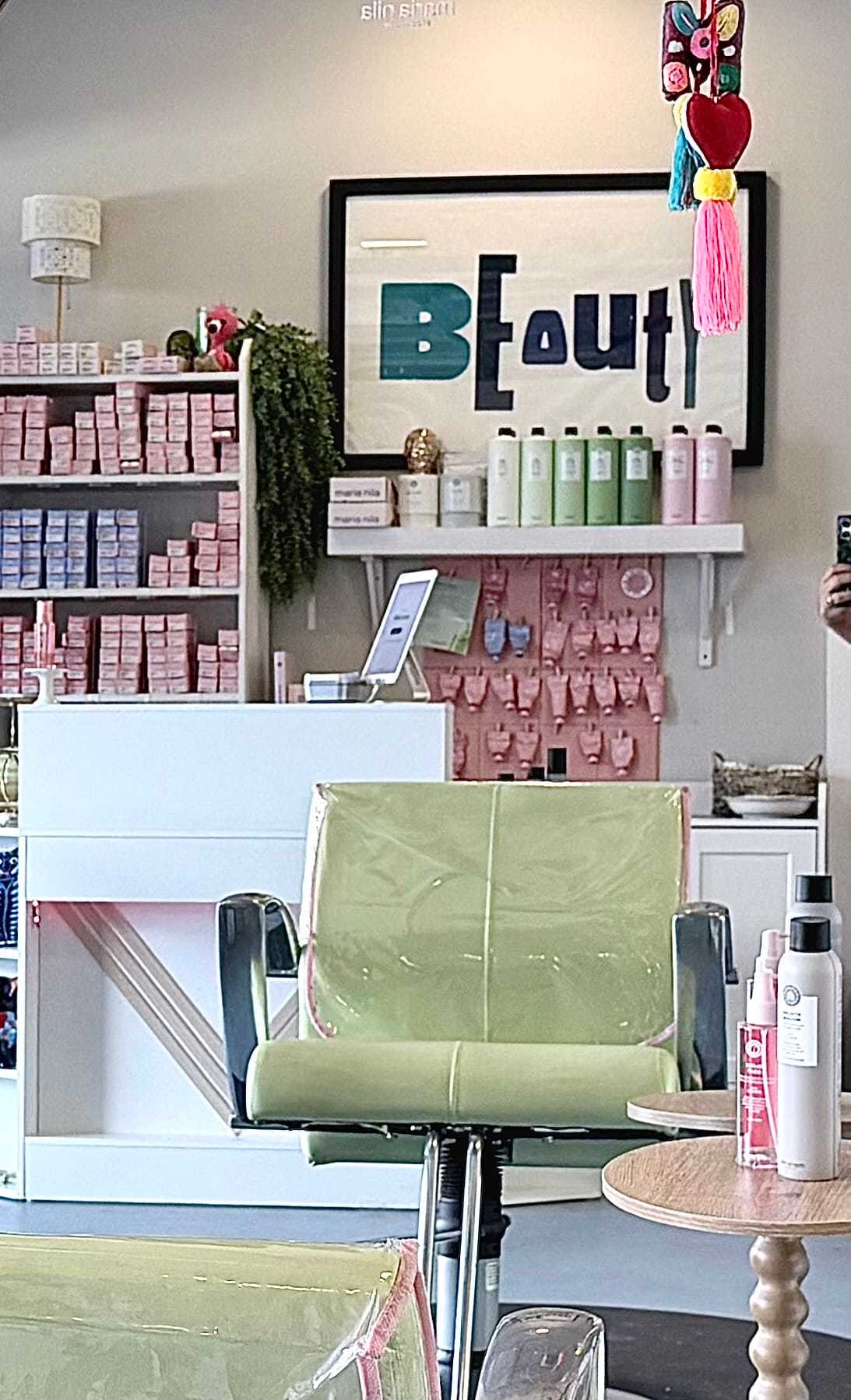 Salon interior with green chair, products on shelves, and a "BEauti" sign.
